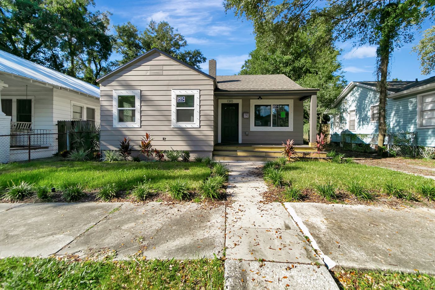 Bungalow exterior with a front porch, landscaped garden beds, and a walkway