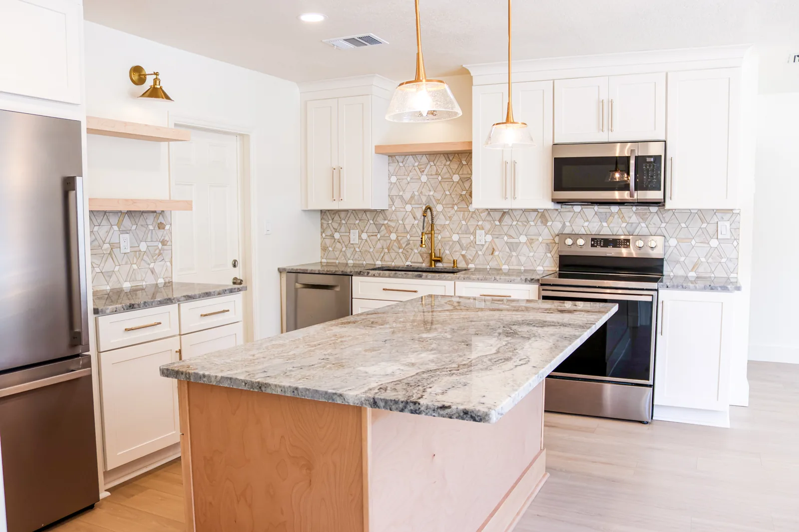 Finished Bay View kitchen with a stone island, patterned backsplash, and pendant lighting